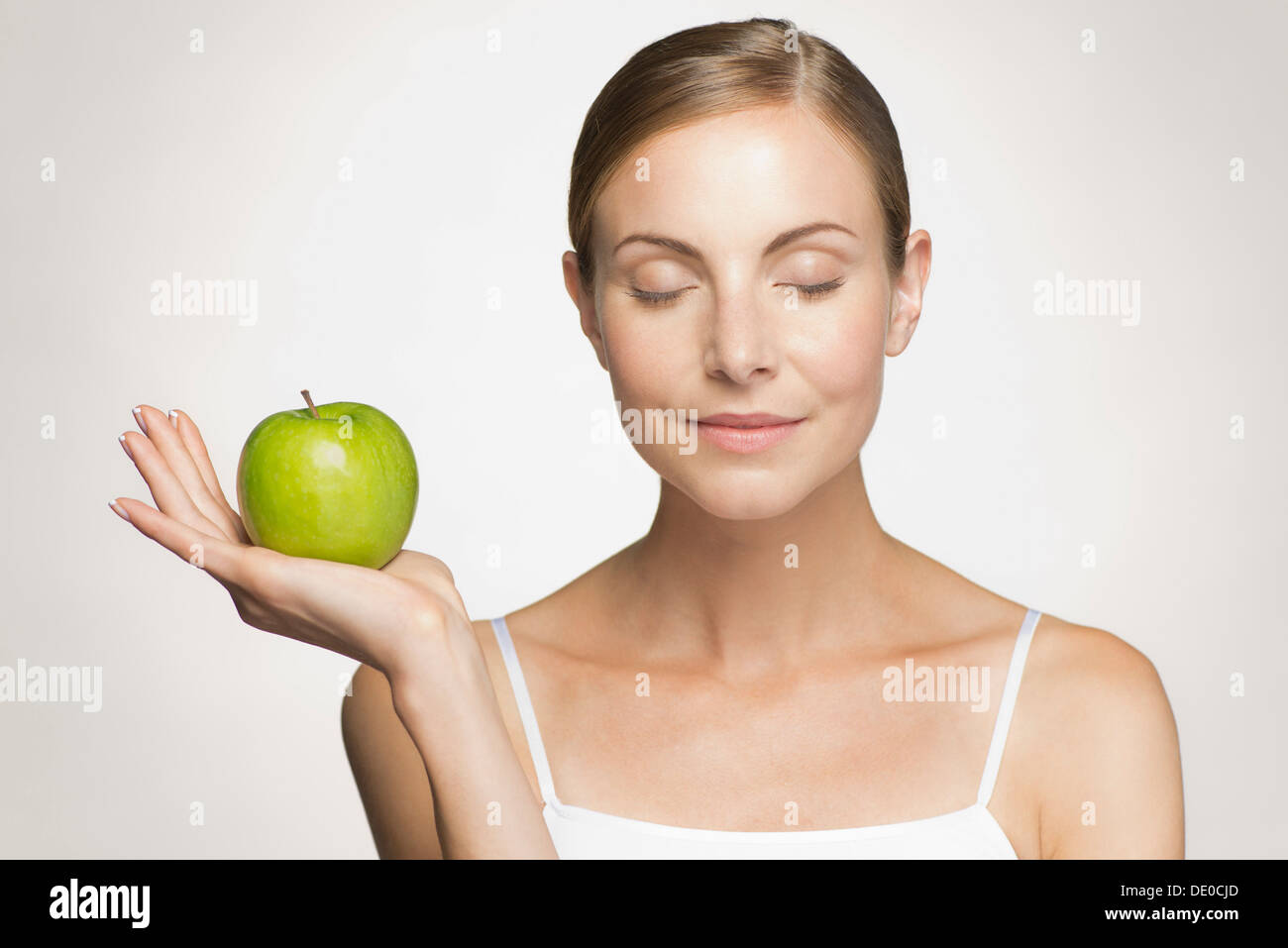 Mujer joven con ojos cerrados la celebración de manzana verde Foto de stock