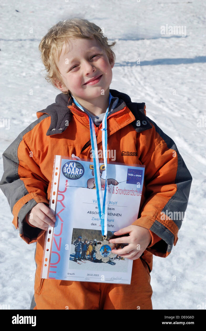 Chico, 5, está encantado con su certificado de ganador después de una carrera de esquí Foto de stock