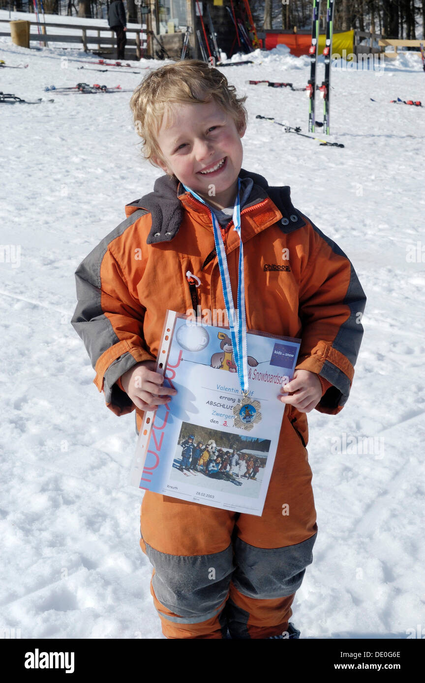 Chico, 5, está encantado con su certificado de ganador después de una carrera de esquí Foto de stock