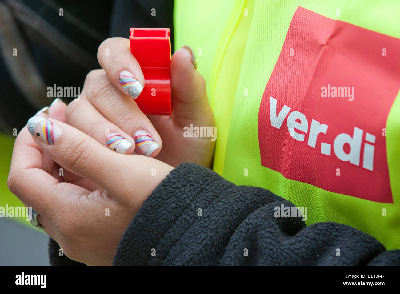 Mujer sosteniendo un silbato, vistiendo un alto-viz jacked con el sindicato ver.di logo Foto de stock