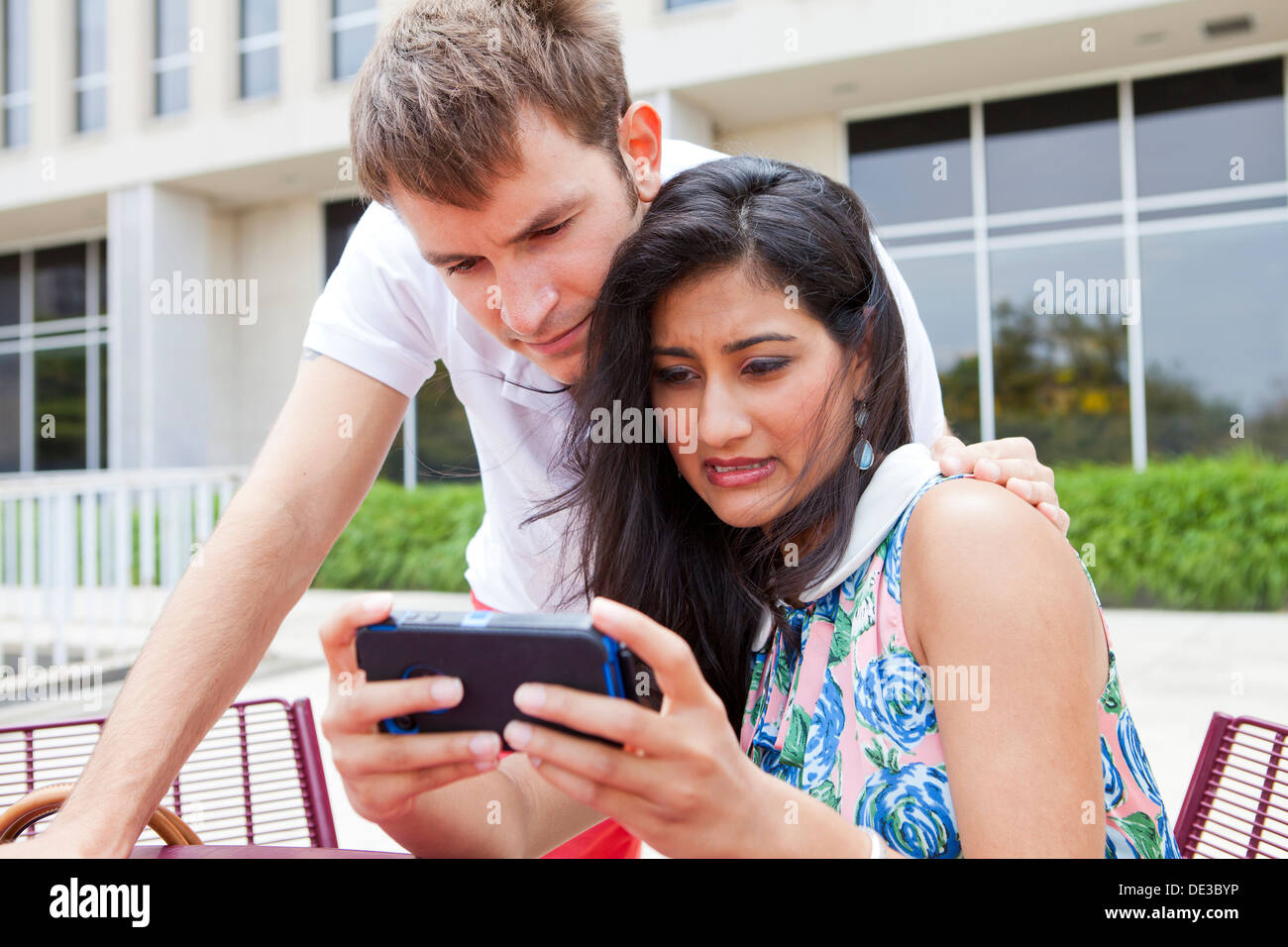 Interesados pareja joven busca en el teléfono inteligente. Foto de stock