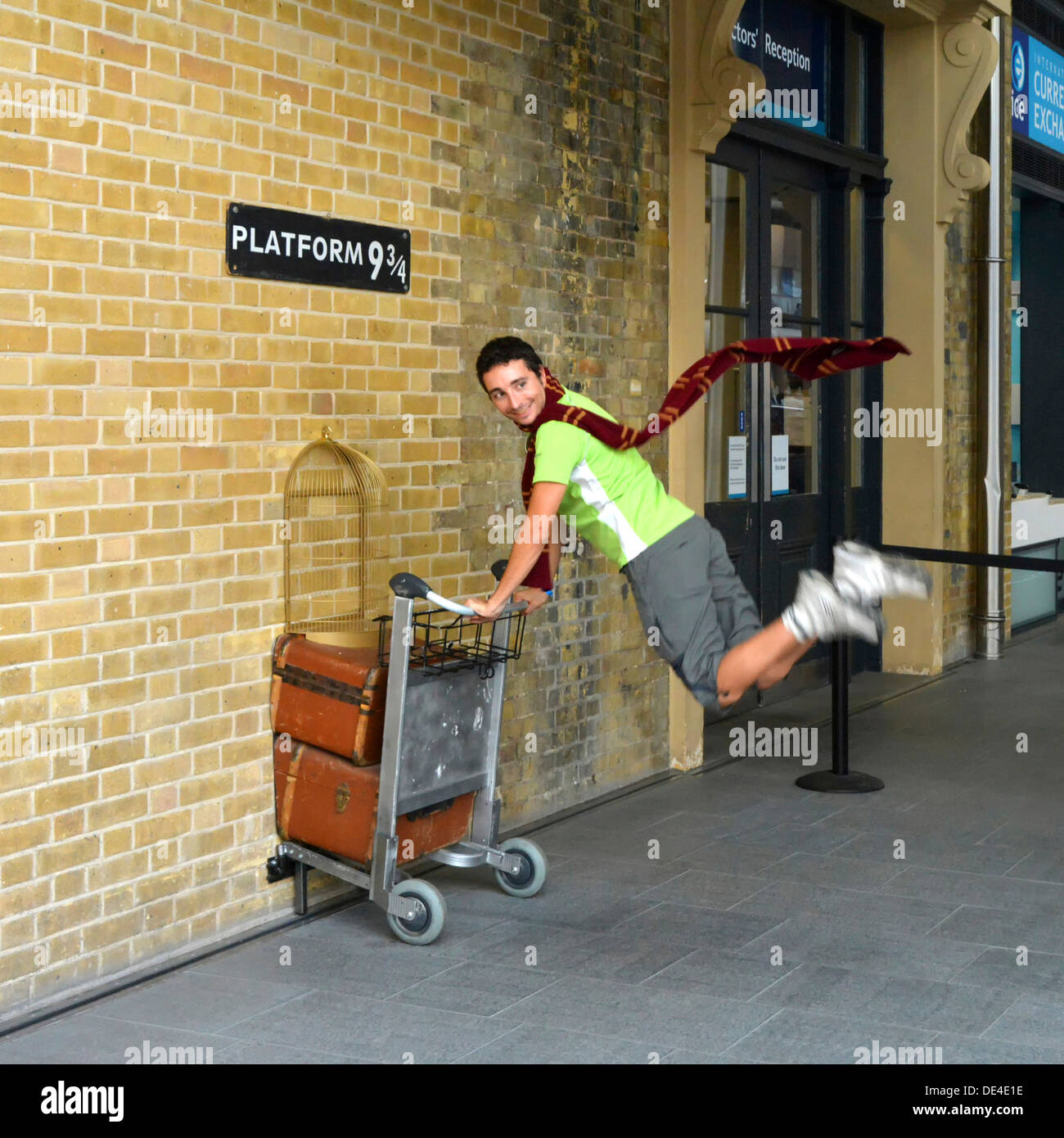 Harry Potter fan recrea empujando un carro hacia la plataforma nueve y tres cuartas partes de la película, la estación de tren de Kings Cross de Londres Inglaterra Foto de stock