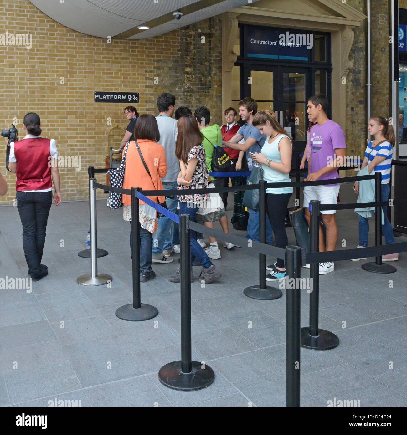 Fans haciendo cola para tener una foto tomada en la plataforma nueve y tres cuartos sign desde historia de Harry Potter en la estación Kings Cross Foto de stock
