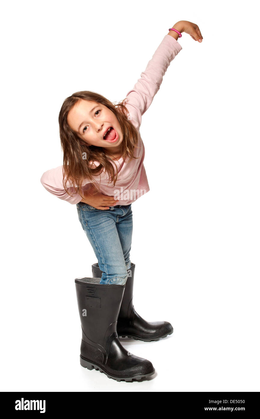 Niña de siete años vistiendo botas de goma que son demasiado grandes Foto de stock
