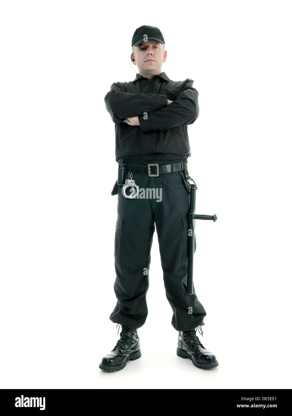 Hombre de seguridad vistiendo uniforme negro equipado con club de policía y esposas de pie con confianza con los brazos cruzados, rodada en blanco Foto de stock