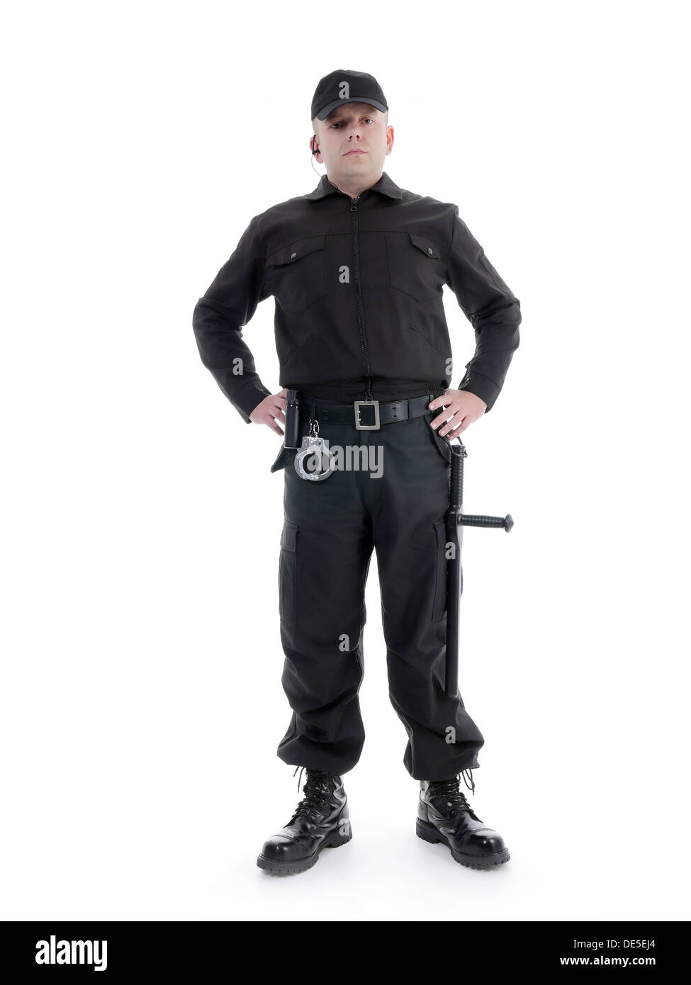 Hombre de seguridad vistiendo uniforme negro equipado con club de policía y esposas de pie con confianza con las manos en la cadera Foto de stock