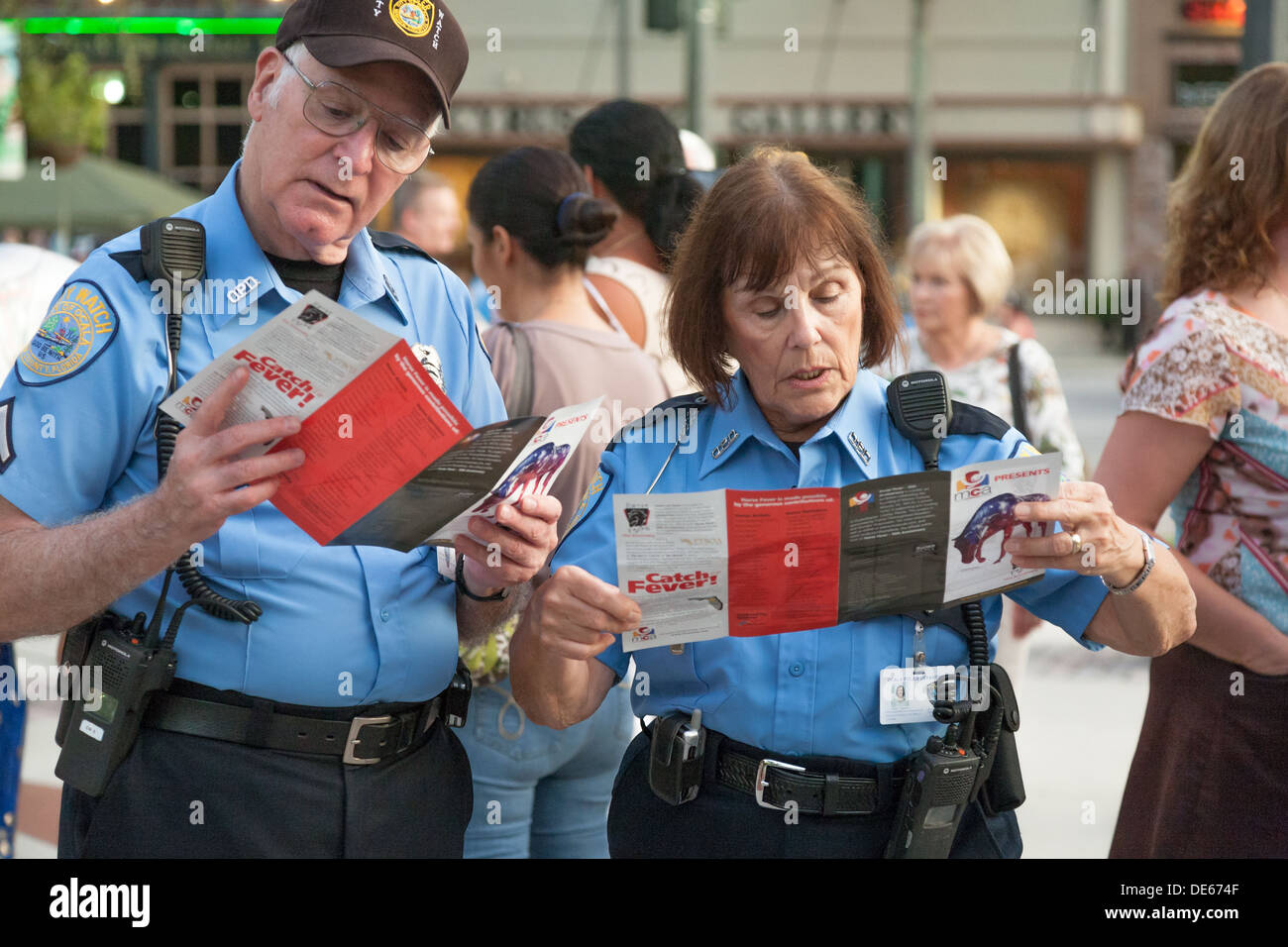Dos oficiales de policía City Watch lectura fiebre caballo folletos en acto público en la plaza del centro de la ciudad de Ocala, Florida Foto de stock