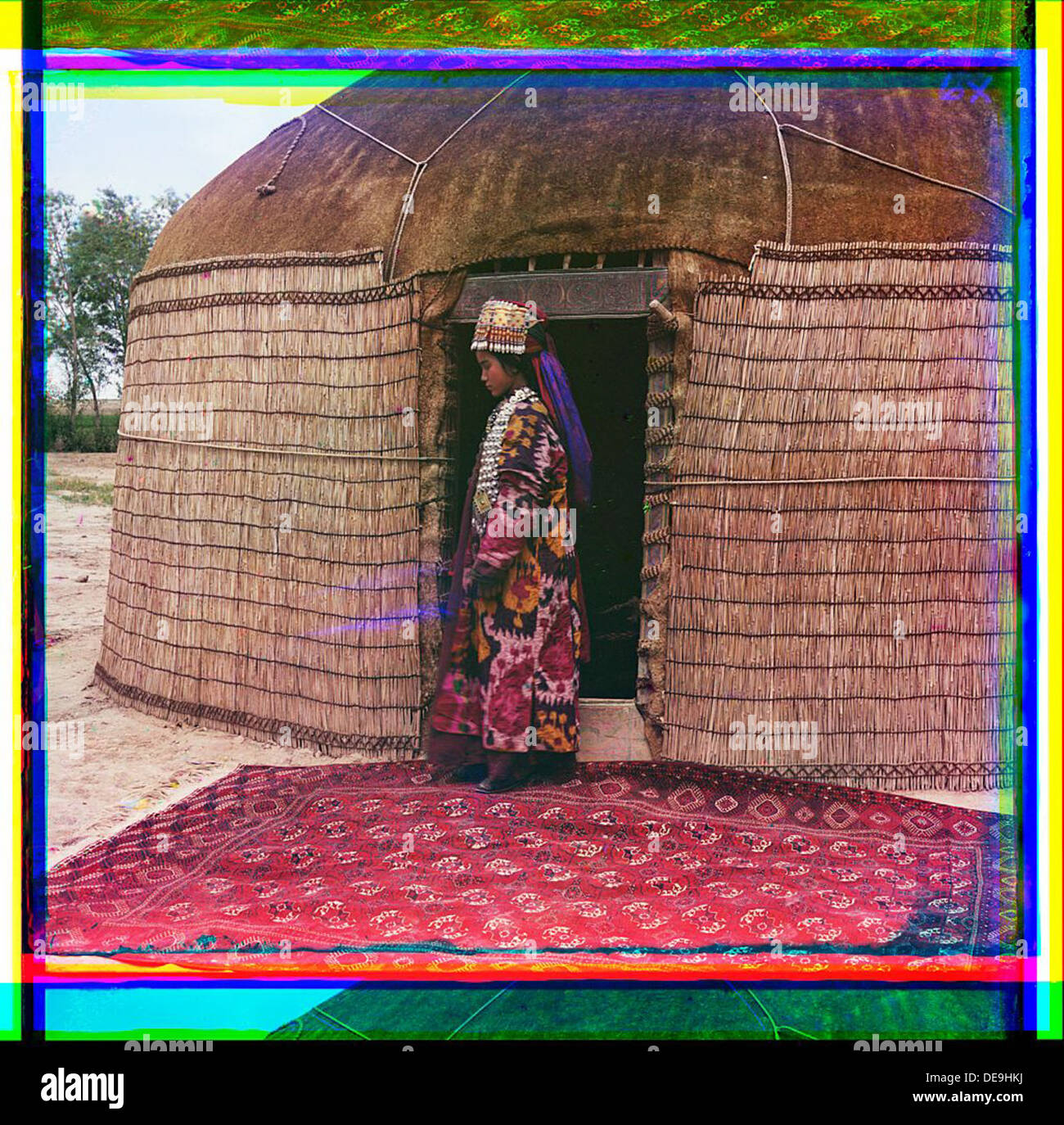 [Perfil de longitud completa el retrato de una mujer, posiblemente turcomanos o Kirgiz, de pie sobre una alfombra en la entrada de una yurta, vestidos con ropas tradicionales y joyas] (LOC) Foto de stock