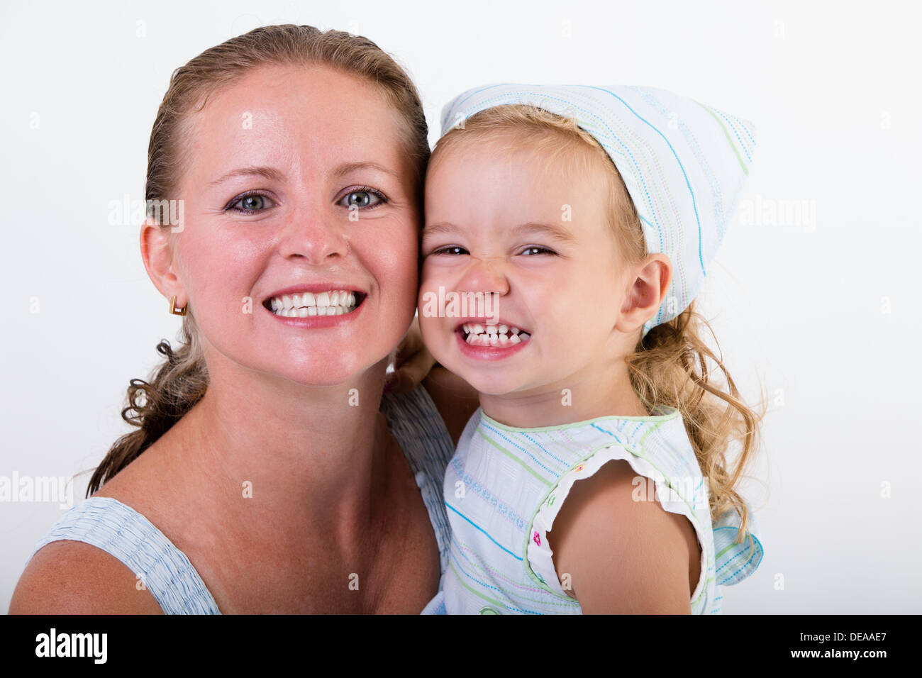 Madre e hija dando un gran gran sonrisa sobre fondo blanco. Foto de stock