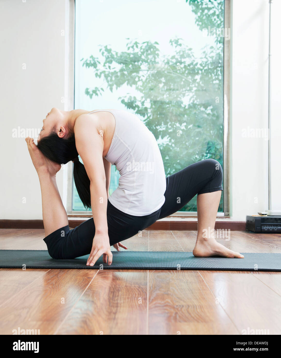 La mujer se inclinó hacia atrás en una posición de yoga en un estudio de yoga, vista lateral Foto de stock