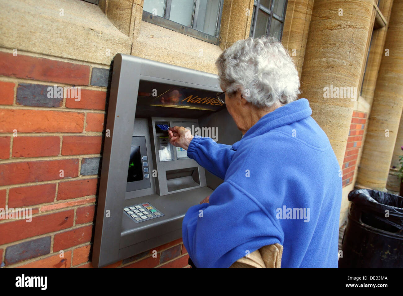 Una mujer senior citizen insertando una tarjeta en un cajero automático Foto de stock