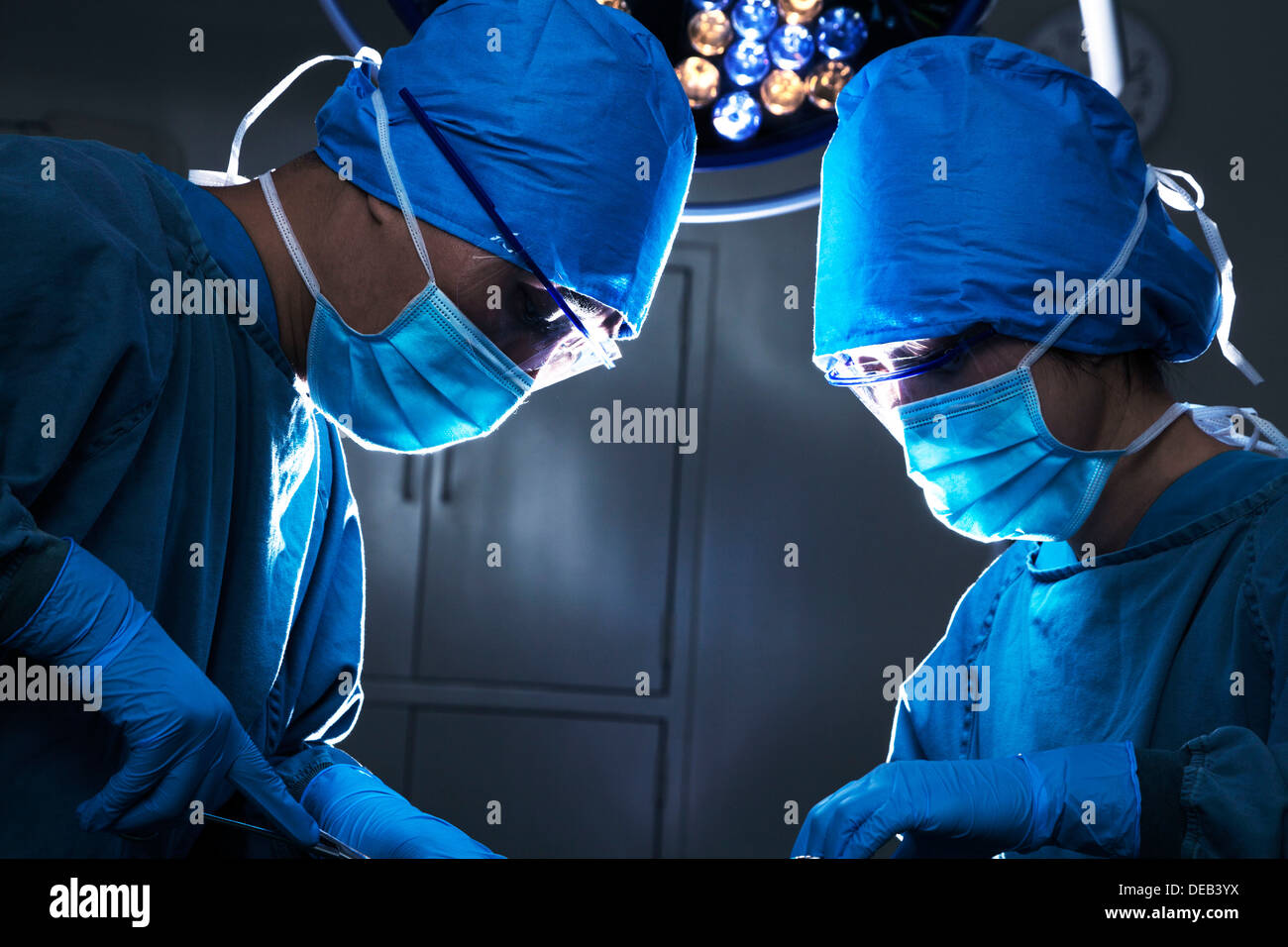 Dos cirujanos mirando hacia abajo, el trabajo y concentrarse en la mesa de operaciones Foto de stock
