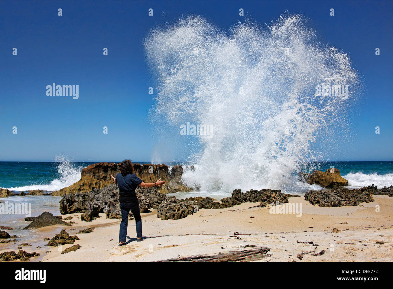 Mujer mirando las olas rompiendo sobre las rocas, en el oeste de Australia Foto de stock
