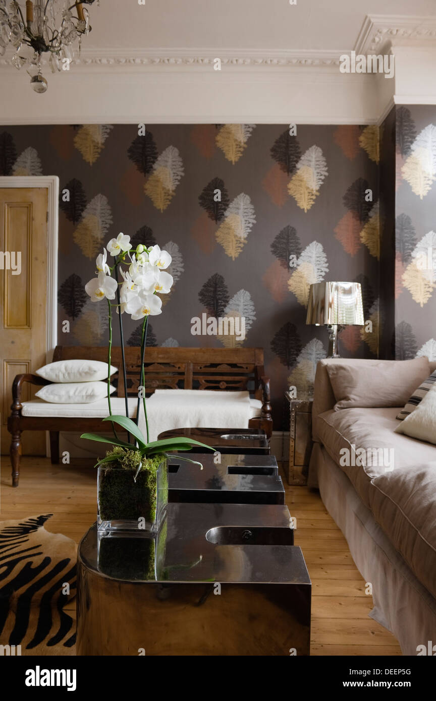 Leaf motif papel tapiz con acabados metálicos en la sala de estar amueblada eclectically Foto de stock