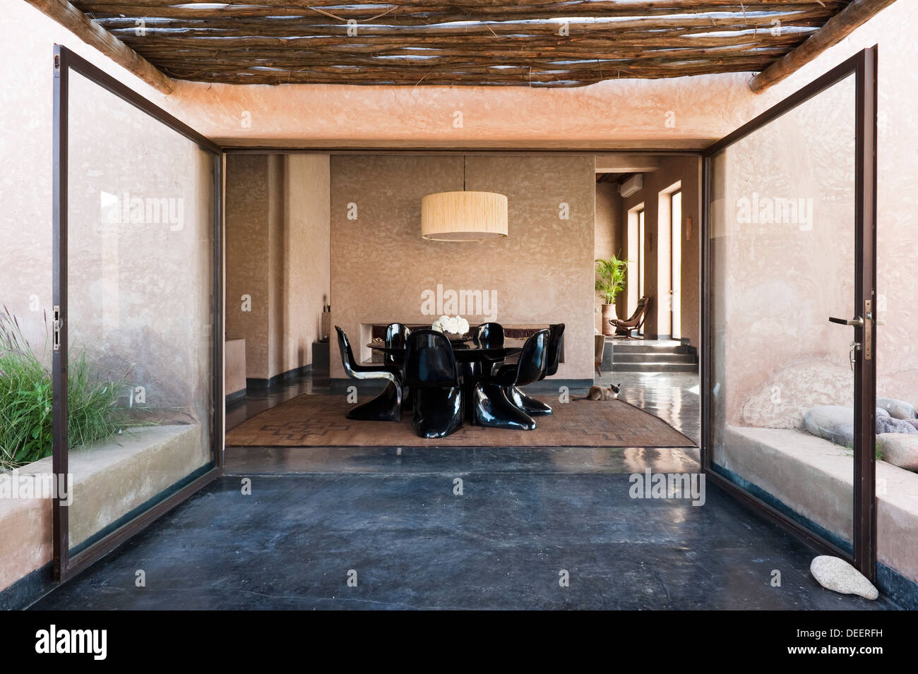 Apertura de puertas de patio de vidrio para la mesa y las sillas en negro brillante. Diseño de interiores y decoración Romain Michel-Meniere Foto de stock