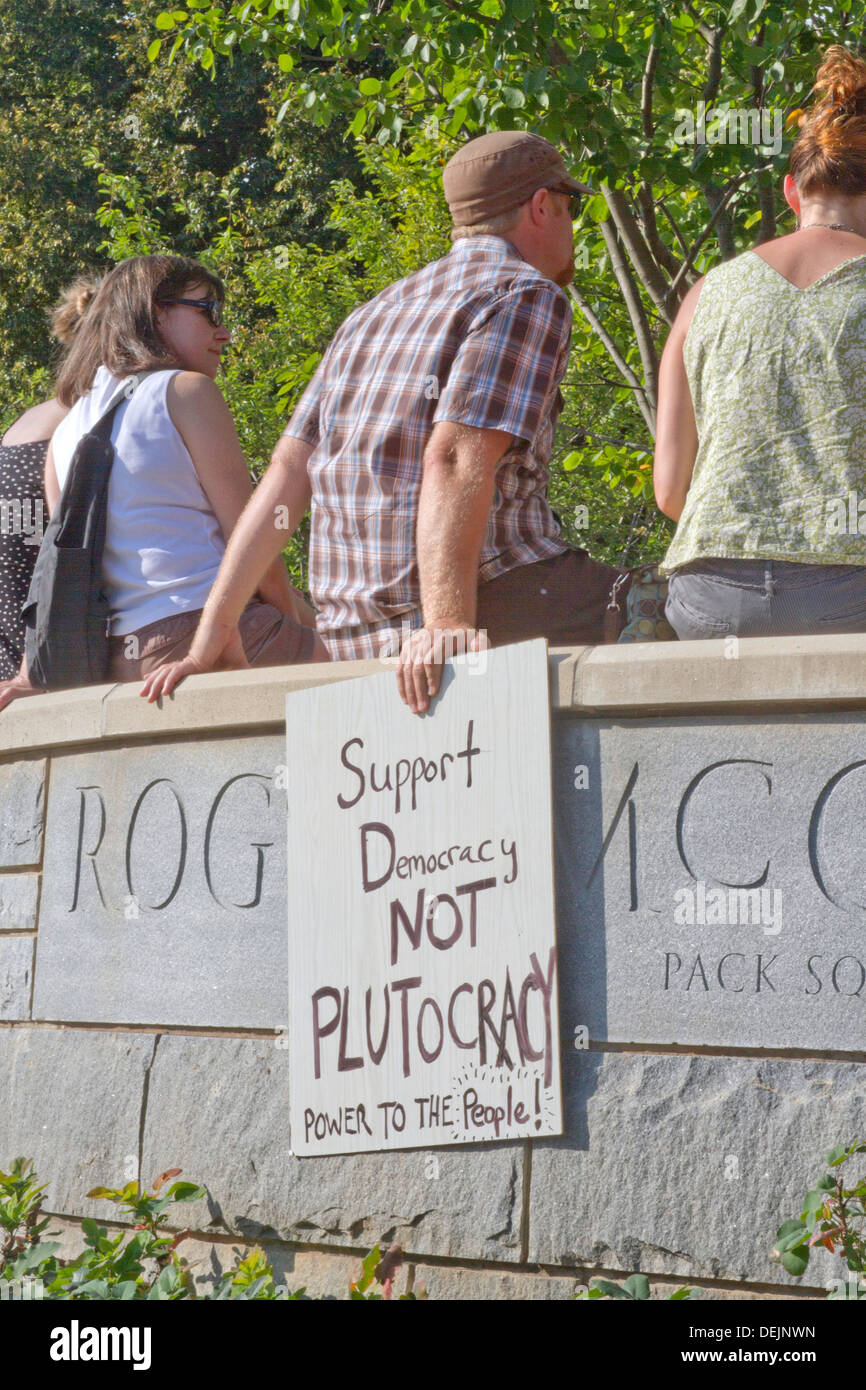 Manifestante masculino muestra un signo político sobre la democracia vs plutocracia moral lunes rally en Asheville en agosto 5, 2013 Foto de stock