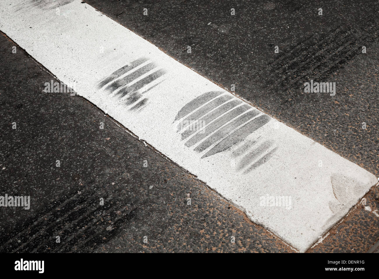 Fragmento de cruce peatonal con banda blanca y los neumáticos de carretera de asfalto Foto de stock