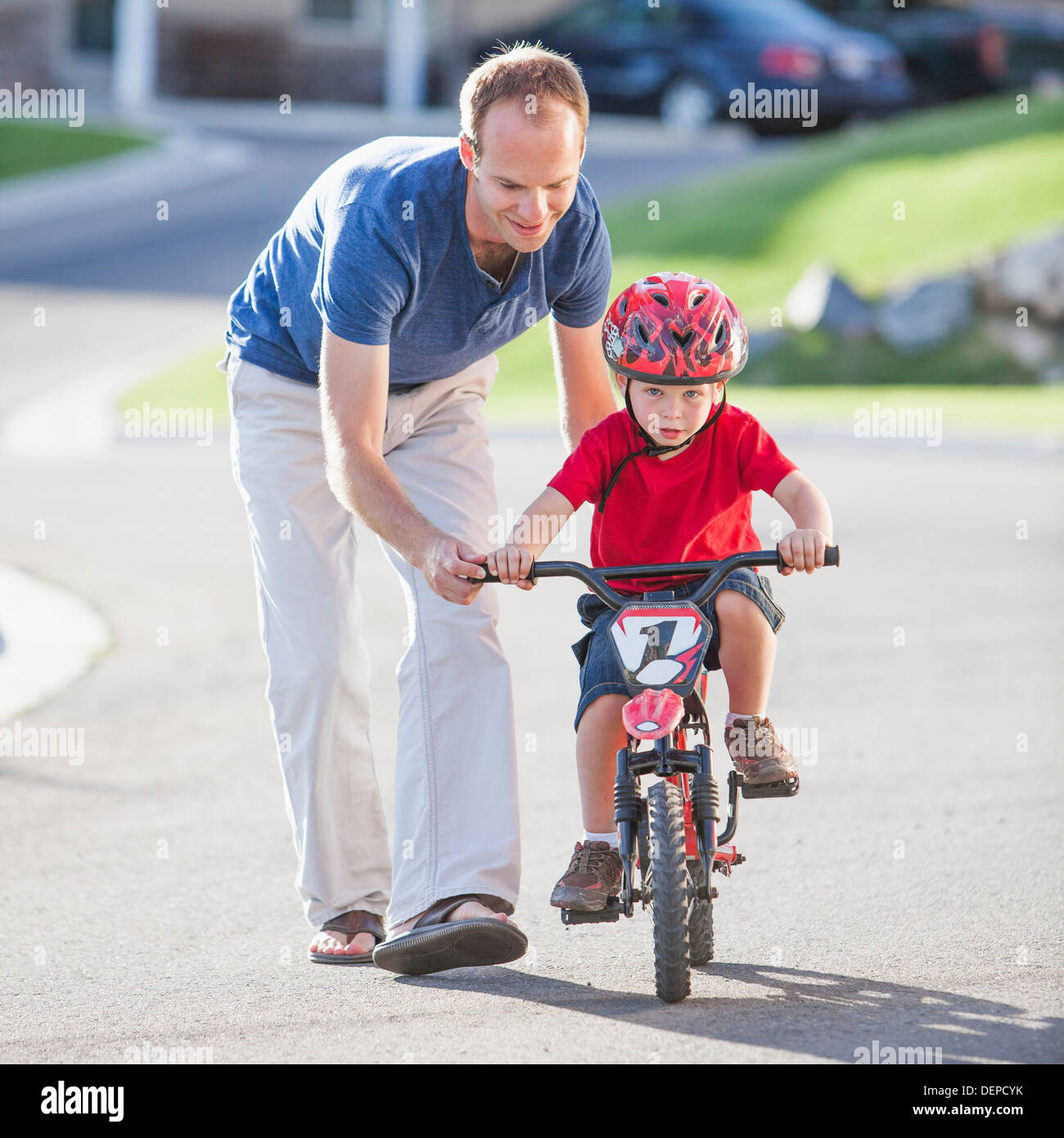 Hijo de padre caucásico enseñando a andar en bicicleta Foto de stock