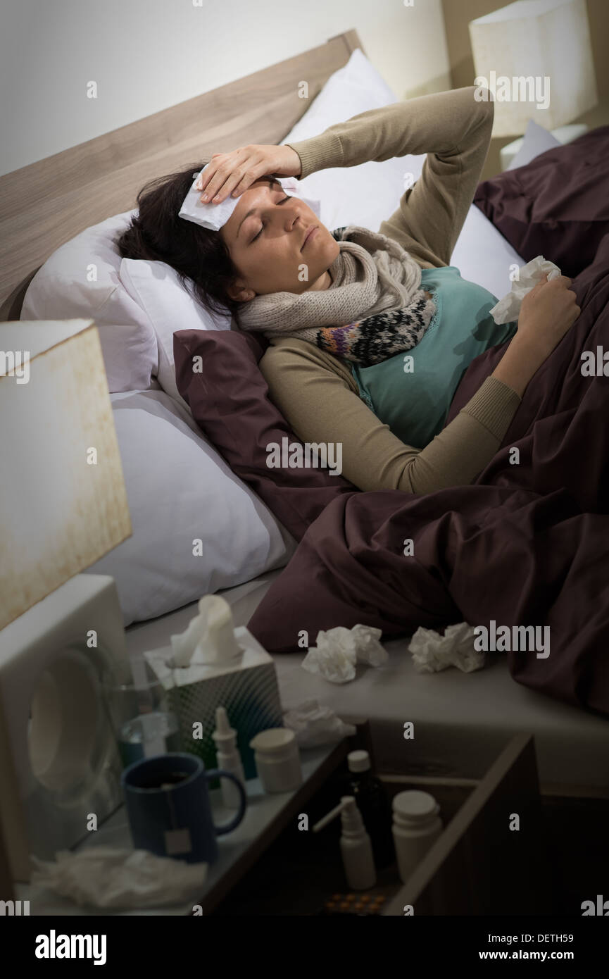 Mujer enferma con gripe acostado en la cama sufriendo de dolor de cabeza Foto de stock