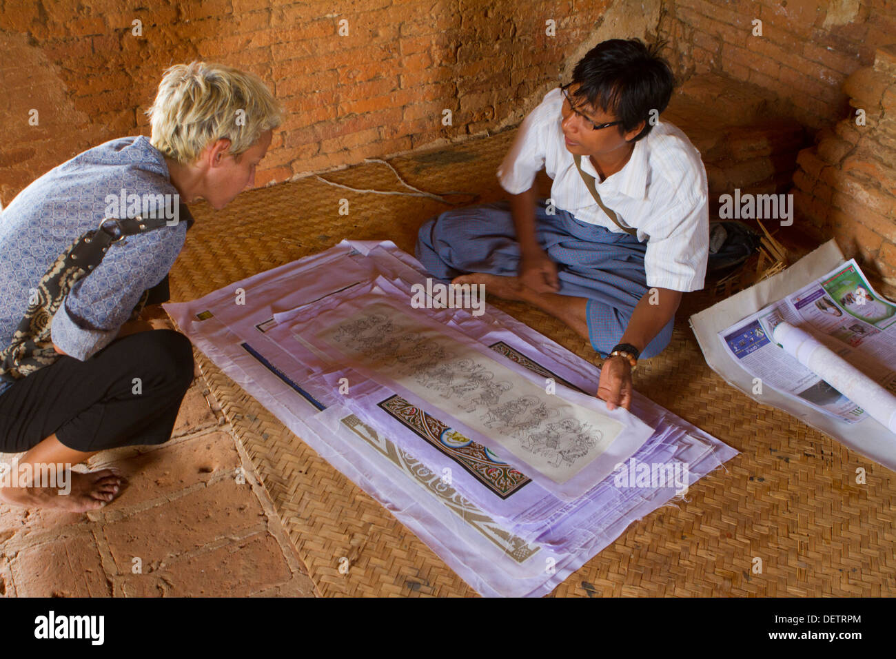 Una mujer un proveedor busca una venta en un pequeño templo en la llanura del norte de Bagan. Foto de stock