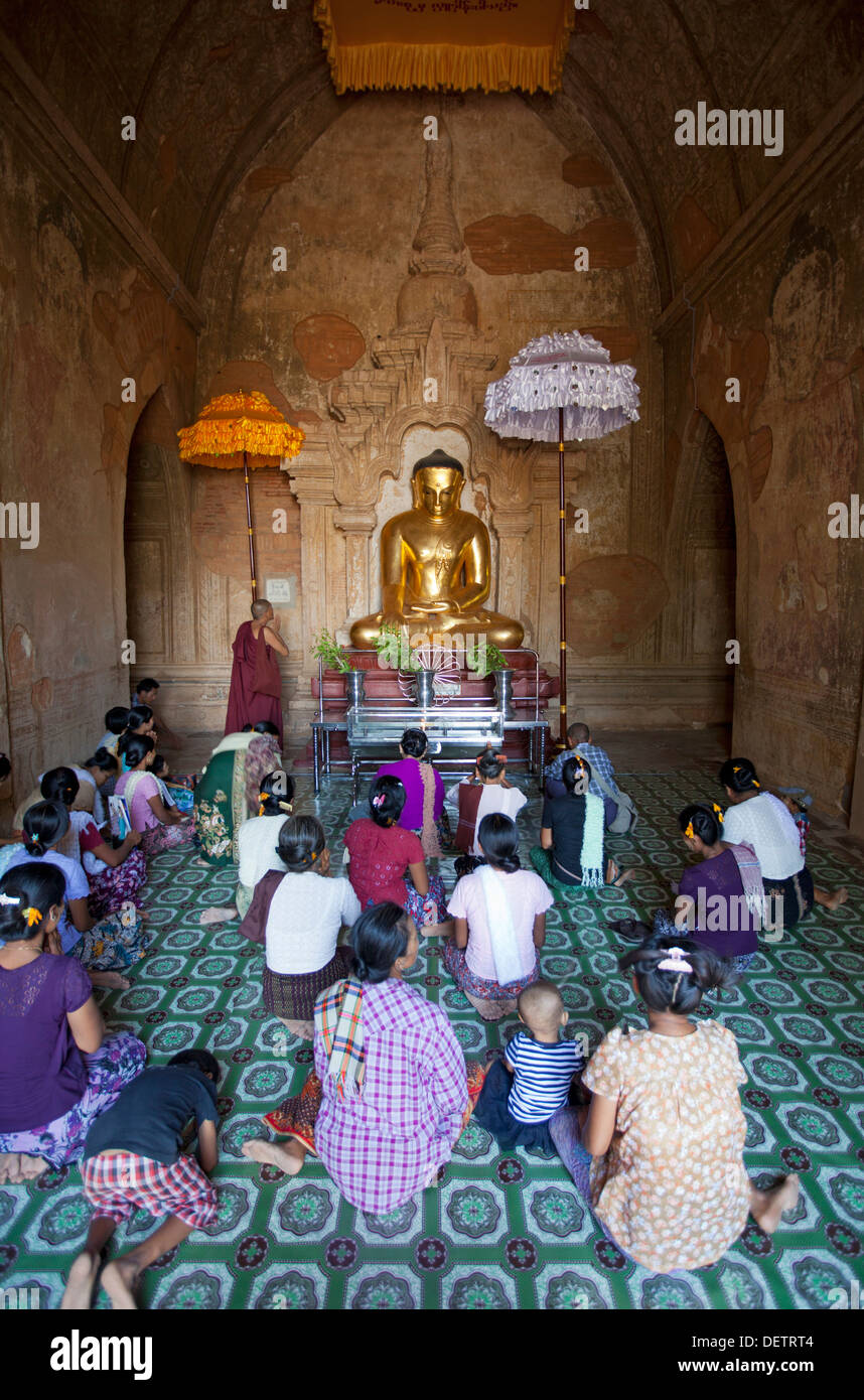 Rezar delante de la imagen de Buda en un templo en la llanura del norte de Bagan. Foto de stock