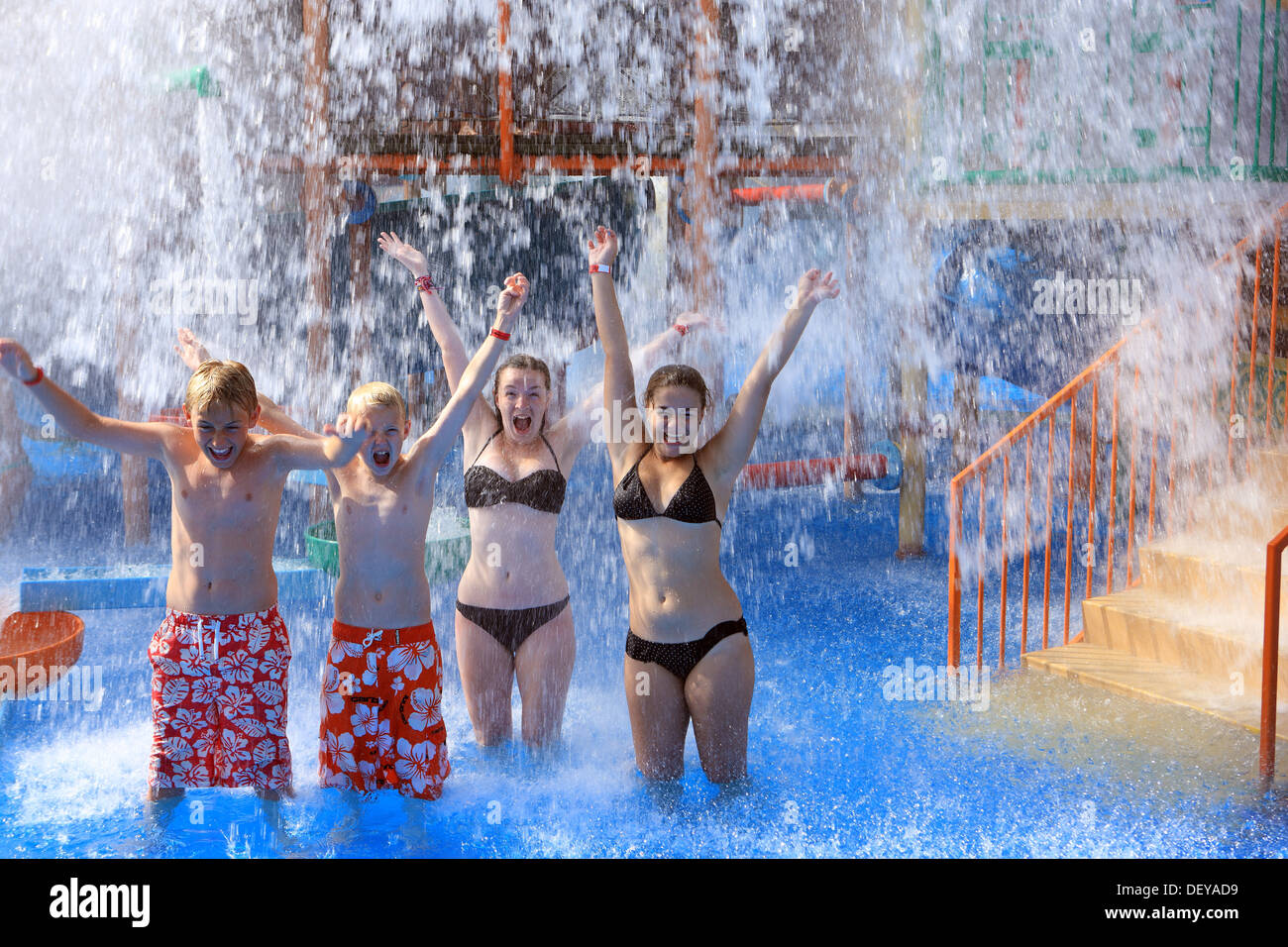 Los jóvenes disfrutando el agua cayendo sobre ellos en un Parque Acuático Foto de stock