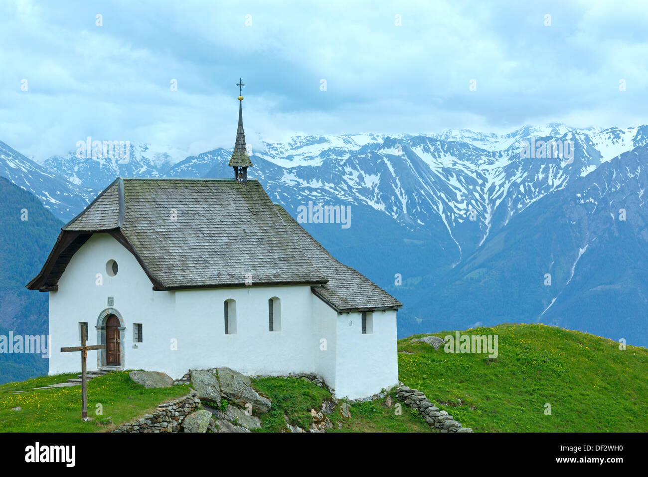 Preciosa Montaña Vieja Iglesia en el pueblo de Bettmeralp (Suiza). Vista nublada de verano. Foto de stock