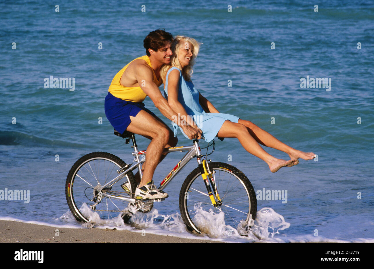 Chica a su novio el manubrio de bicicleta a la orilla del mar Fotografía de  stock - Alamy