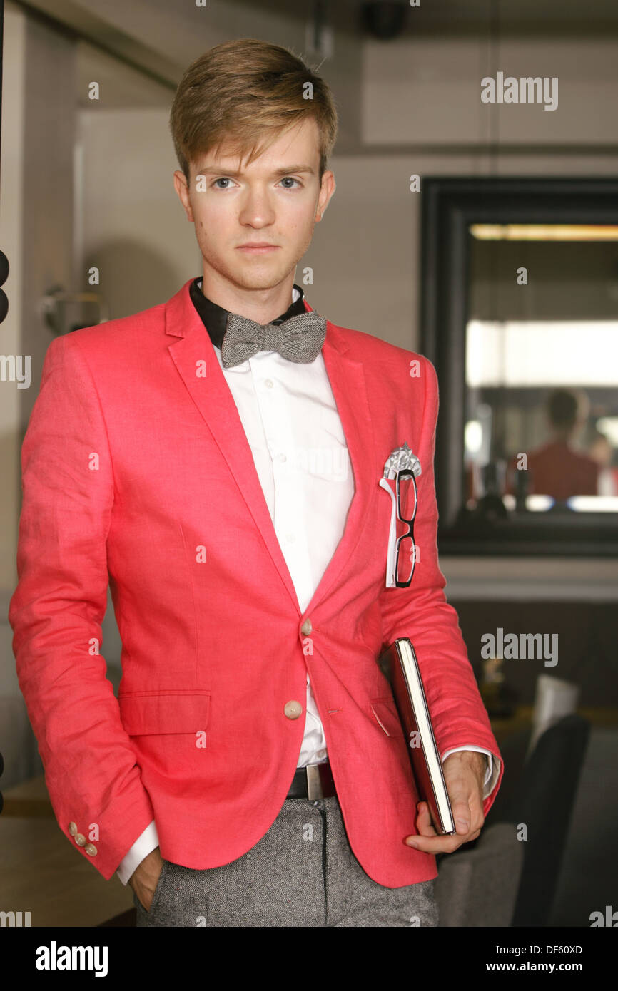 Joven apuesto hombre elegante modelo de moda vestidos de rojo brillante  chaqueta y corbata con portátiles posando para interiores Fotografía de  stock - Alamy