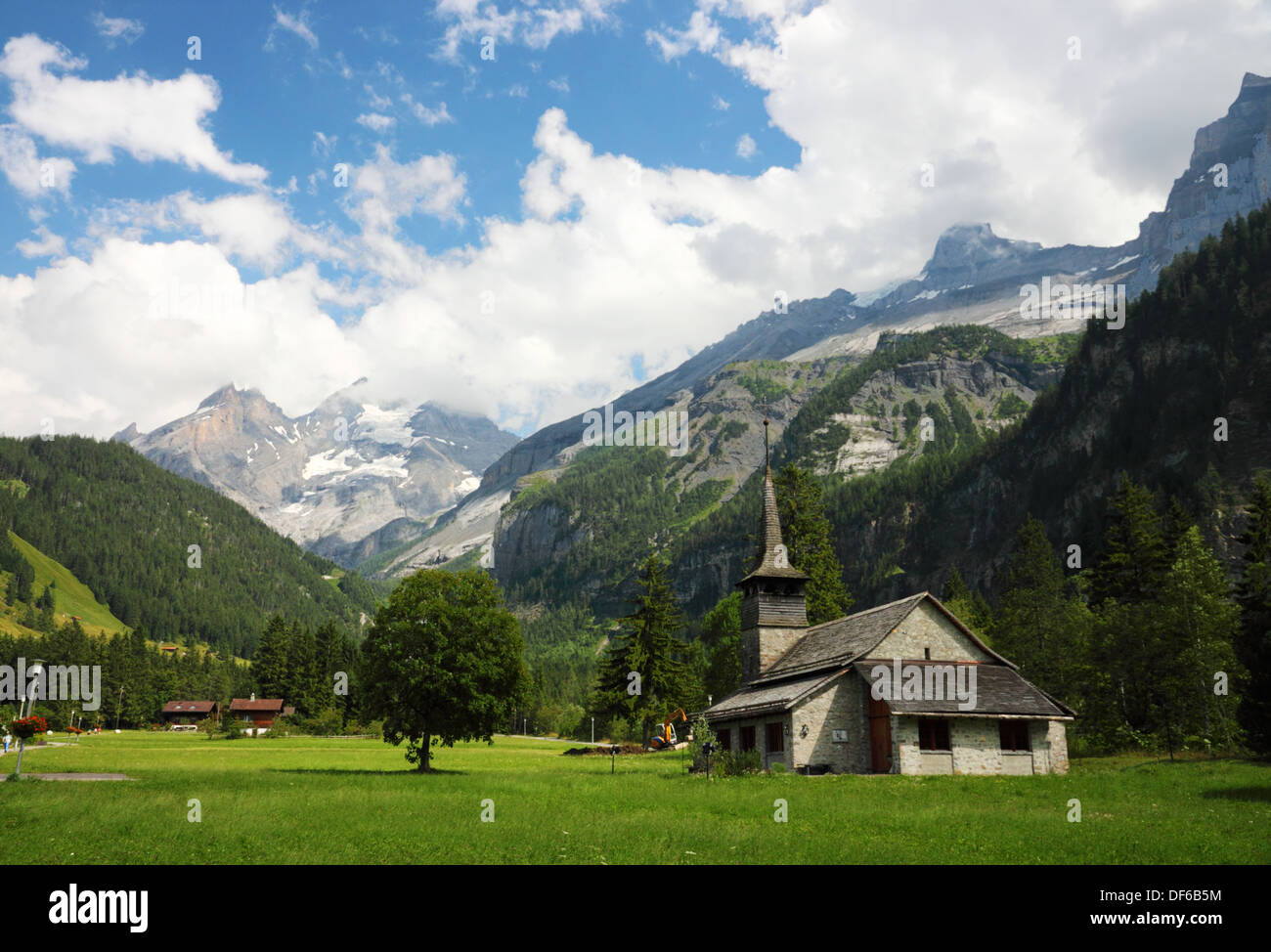 Una iglesia alpino de madera en un valle con montañas en la distancia. Foto de stock