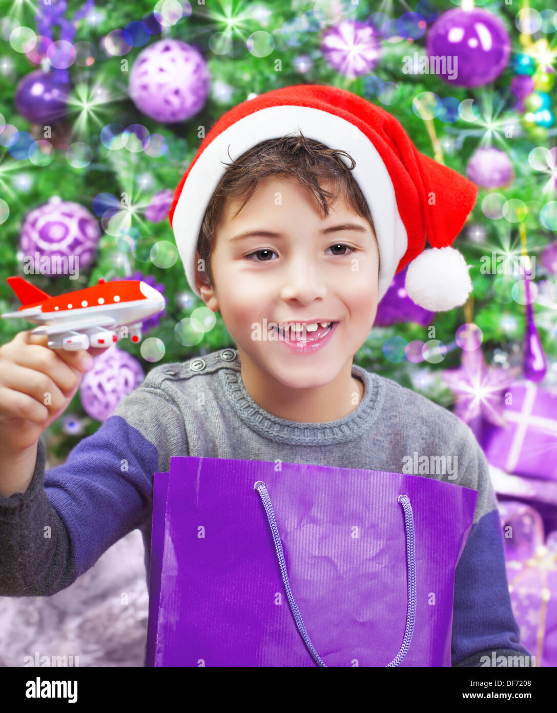 Retrato de niño árabe lindo disfrutando de Navidad Regalo, jugando con pequeños aviones de plástico, vestidos de rojo gorro de Papá Noel Foto de stock