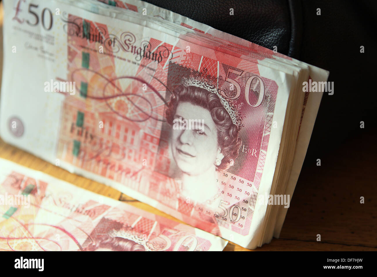 Sterling £50 notas - algunos inclinada contra un bolso y otros tumbado junto a ellos Foto de stock