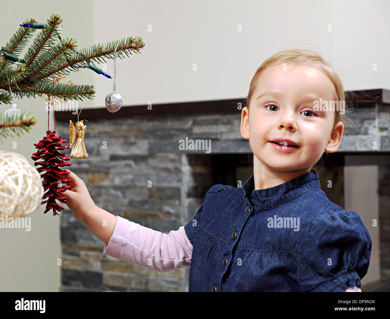 Cute Little Girl decora el árbol de Navidad Foto de stock