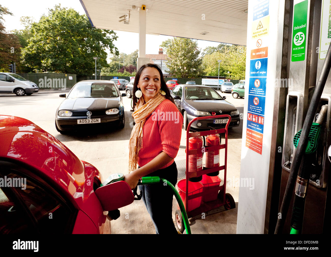 Mujer joven llenar su coche con gasolina sin plomo en una gasolinera, Norwich, Norfolk, UK Foto de stock