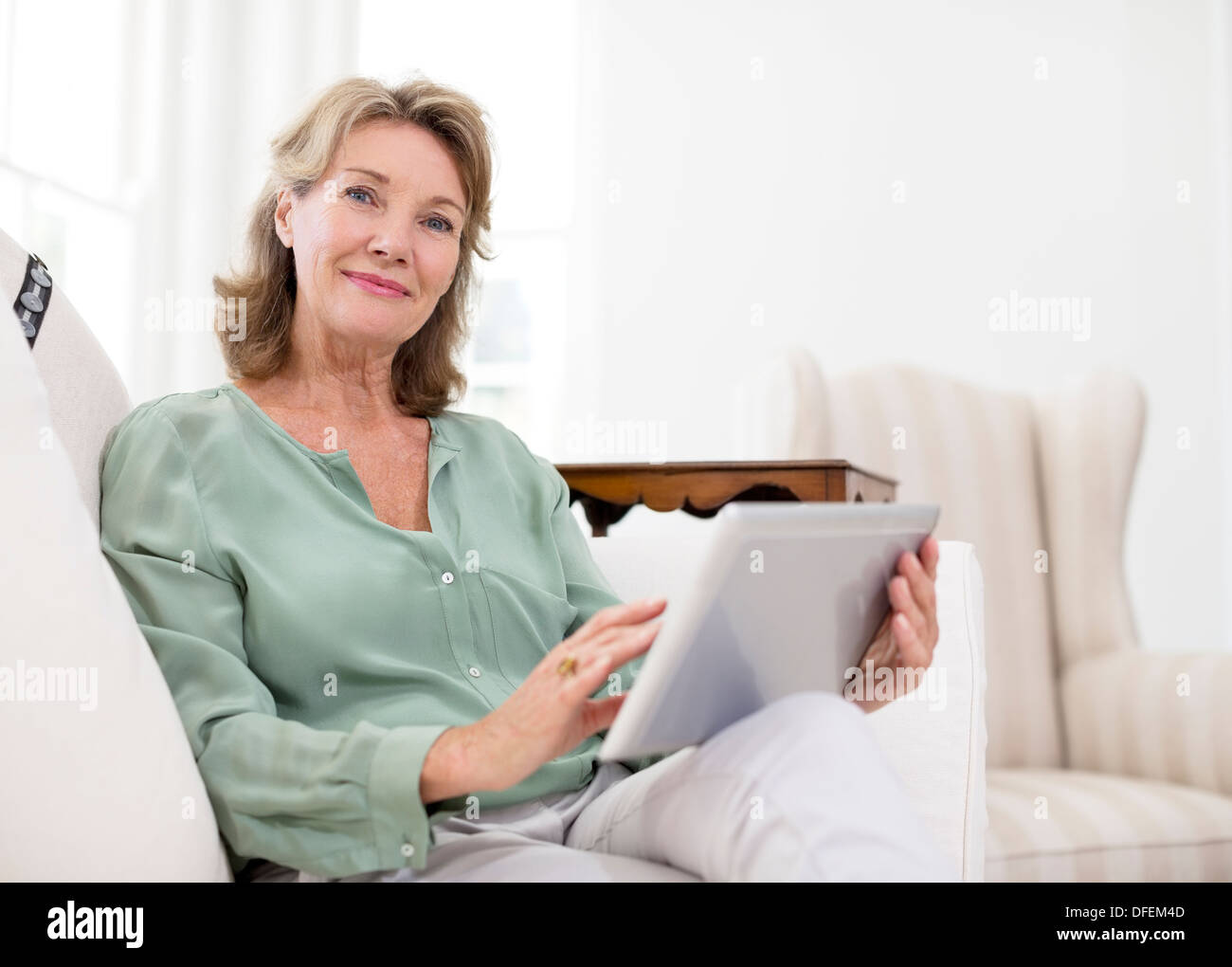 Retrato de mujer mayor utilizando tablet digital en el sofá Foto de stock