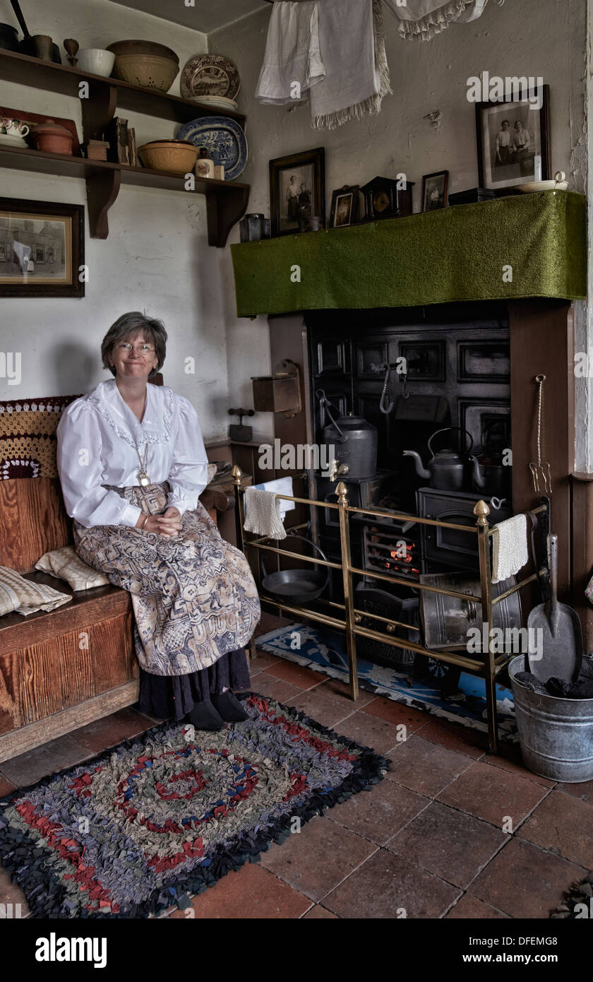 Mujer empleada del Museo de vida Black Country dando la bienvenida a los visitantes en una casa tipo cabaña conservada de 1800/principios de 1900. Sala de la era victoriana Inglaterra Foto de stock