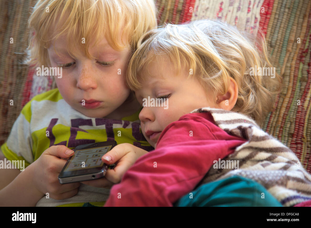 Dos hermanos jugando en un iPhone Foto de stock
