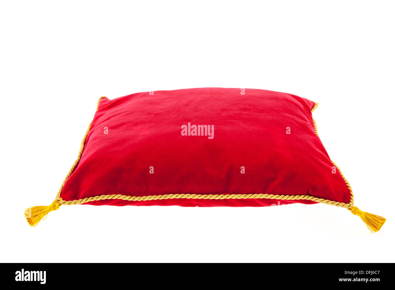 Royal almohada de terciopelo rojo con cuerda de oro aislado sobre fondo blanco. Foto de stock