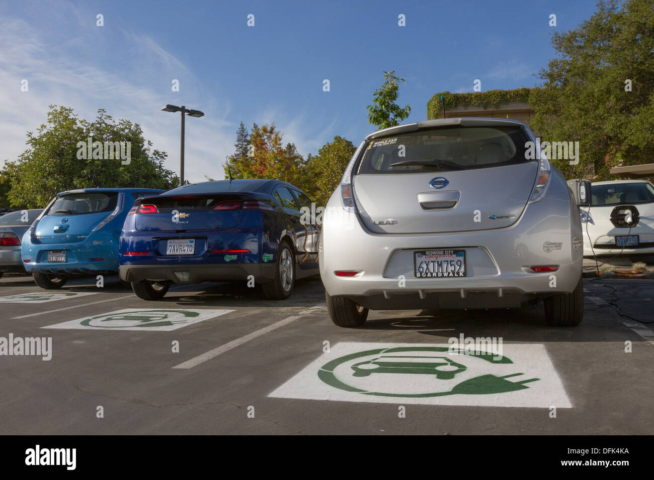 Símbolo EV pintado sobre plazas de aparcamiento para coches eléctricos plug-in en un estacionamiento de la empresa Foto de stock