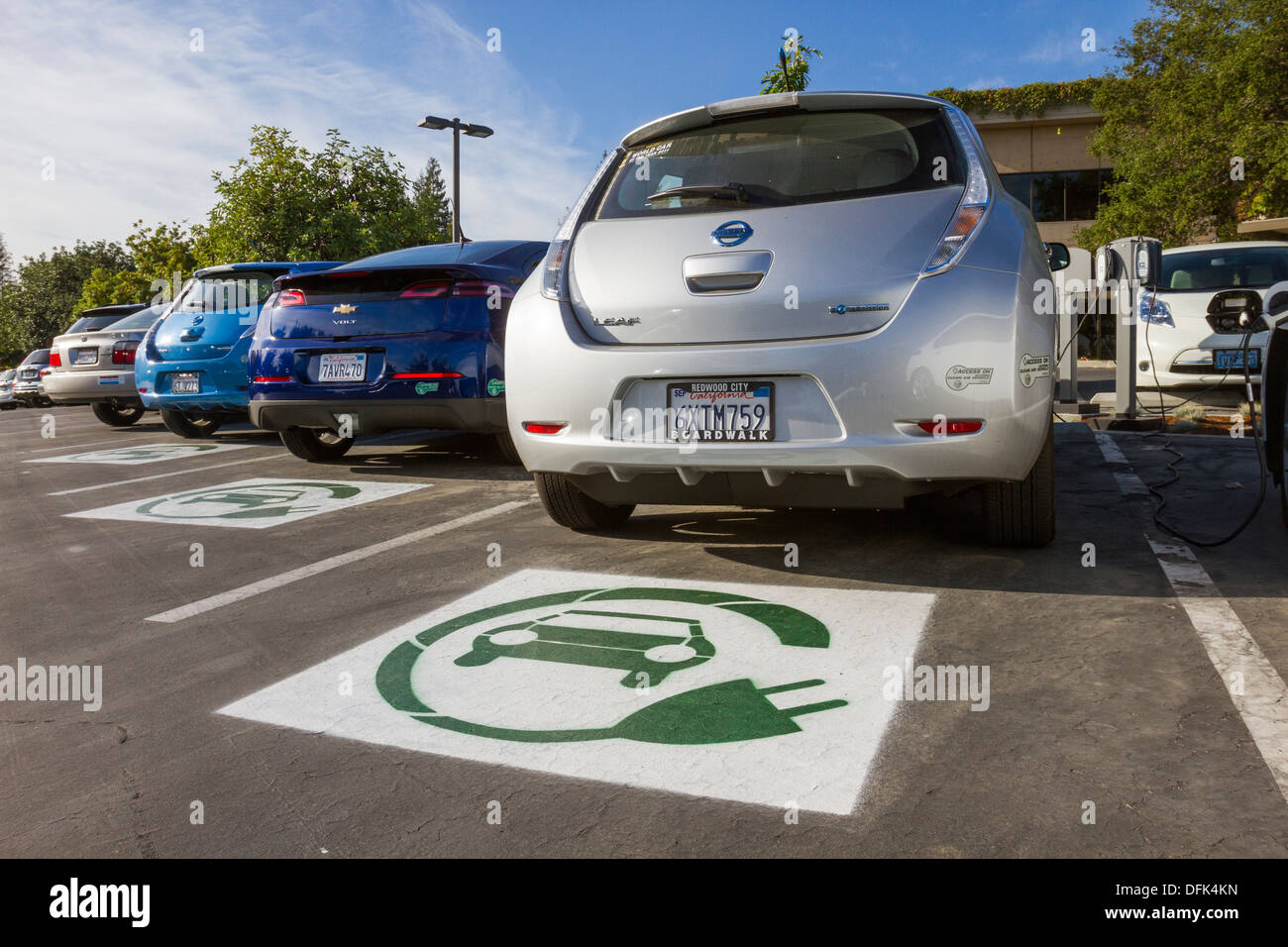 Símbolo EV pintado en plazas reservadas para coches eléctricos plug-in en un estacionamiento de la empresa Foto de stock