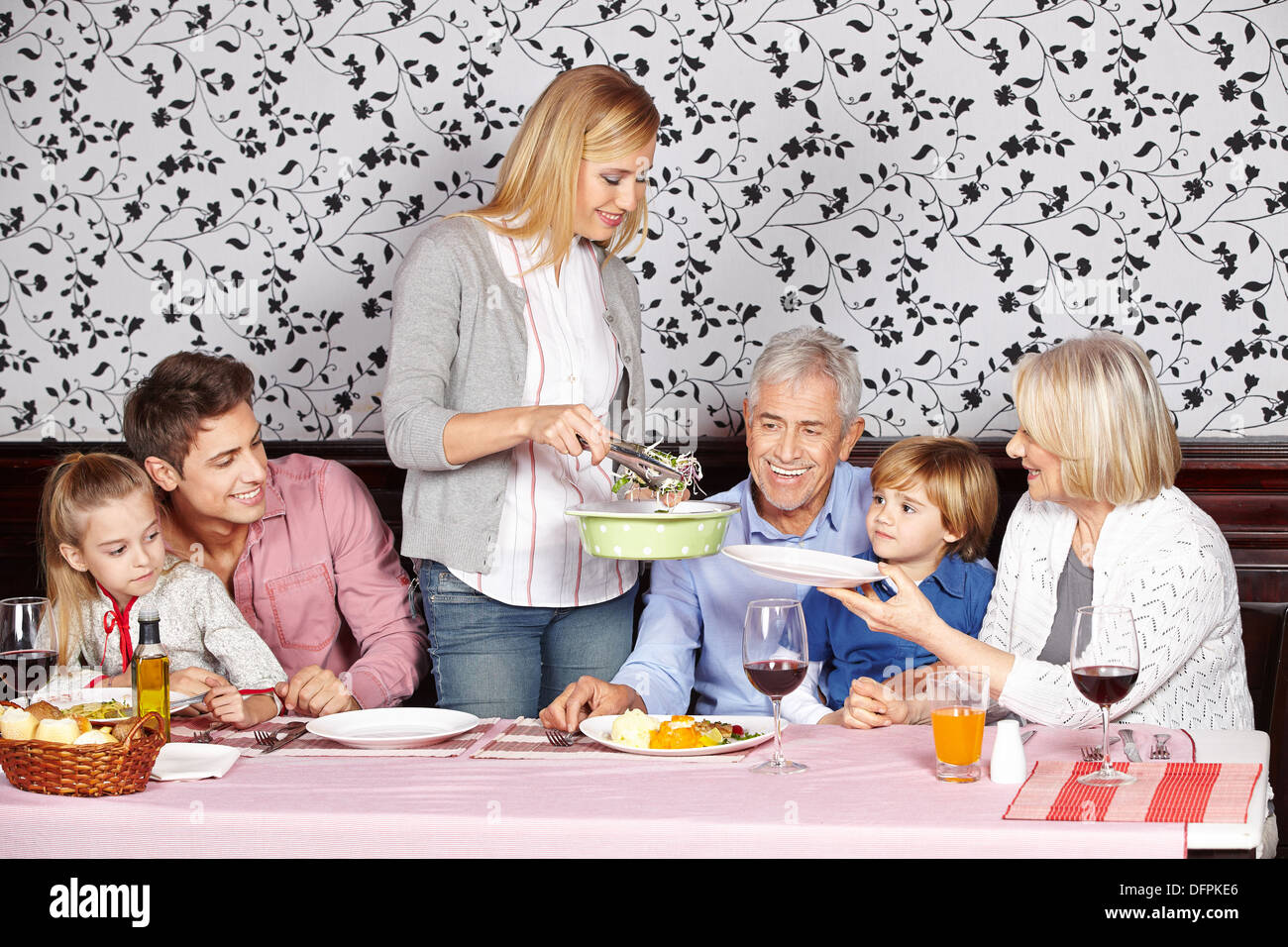 Madre sirviendo comida sana a su familia en la mesa Foto de stock