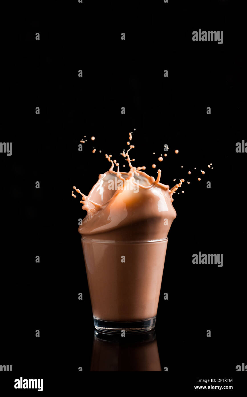 Chocolate con leche splash aislados en negro Foto de stock