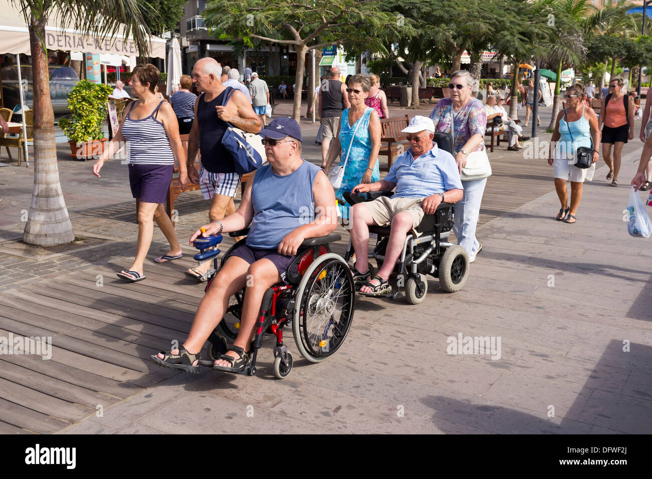 Los discapacitados en sillas de ruedas, pasando por el paseo marítimo de  Los Cristianos, Tenerife, Islas Canarias, España Fotografía de stock - Alamy