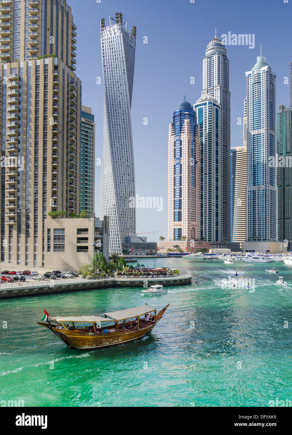 Una embarcación dhow navega alrededor de Dubai Marina de las hidrovías del jet ski siguiente bajo los rascacielos y el paseo del puerto deportivo de Dubai Foto de stock
