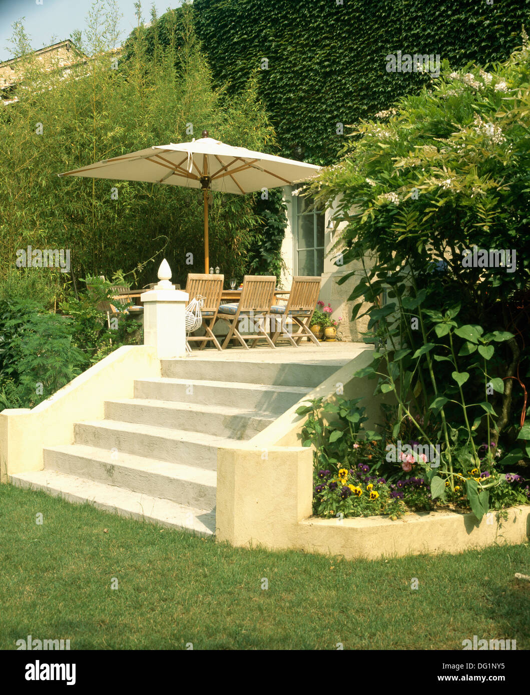 Escalones de piedra que conduce de césped y patio con mesa y sillas