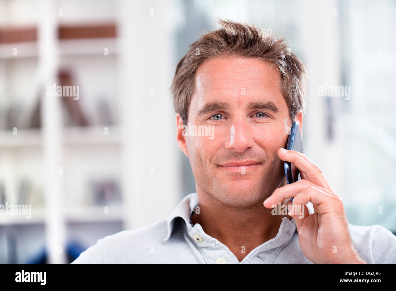 Macho maduro feliz hablando por teléfono móvil en interiores Foto de stock