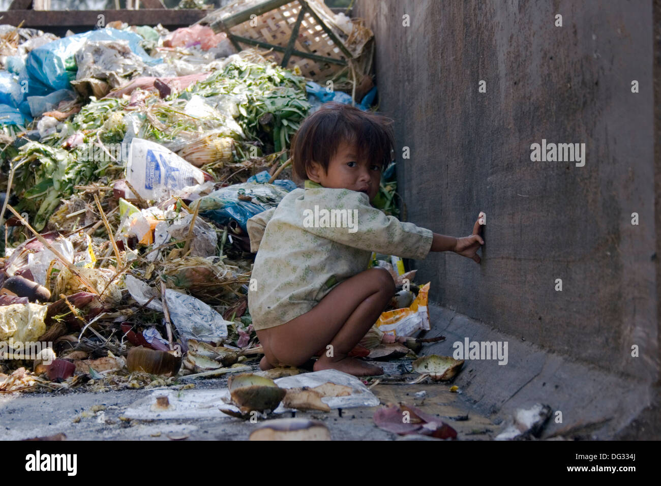 Una joven es defecar en un contenedor lleno de basura en una calle de