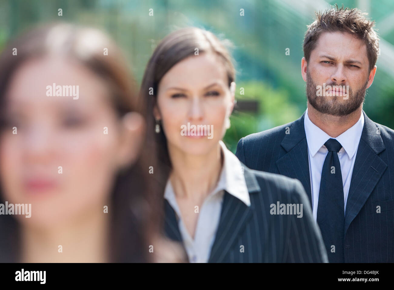 Un hombre de negocios joven empresario con barba esperando detrás de dos mujeres empresarias en línea Foto de stock