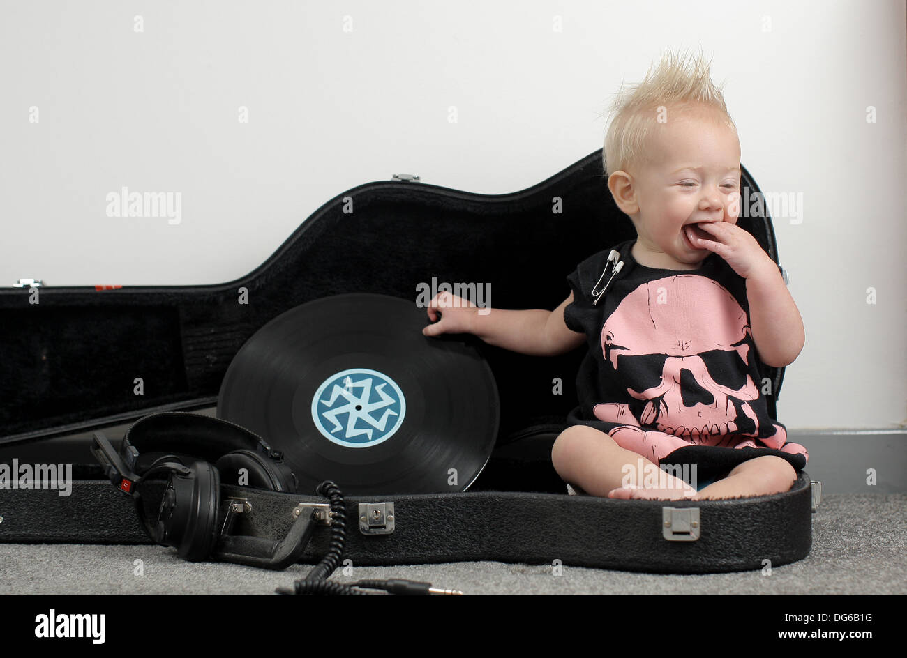 Bebé vestido como un rockero punk sentado en un caso de guitarra Foto de stock