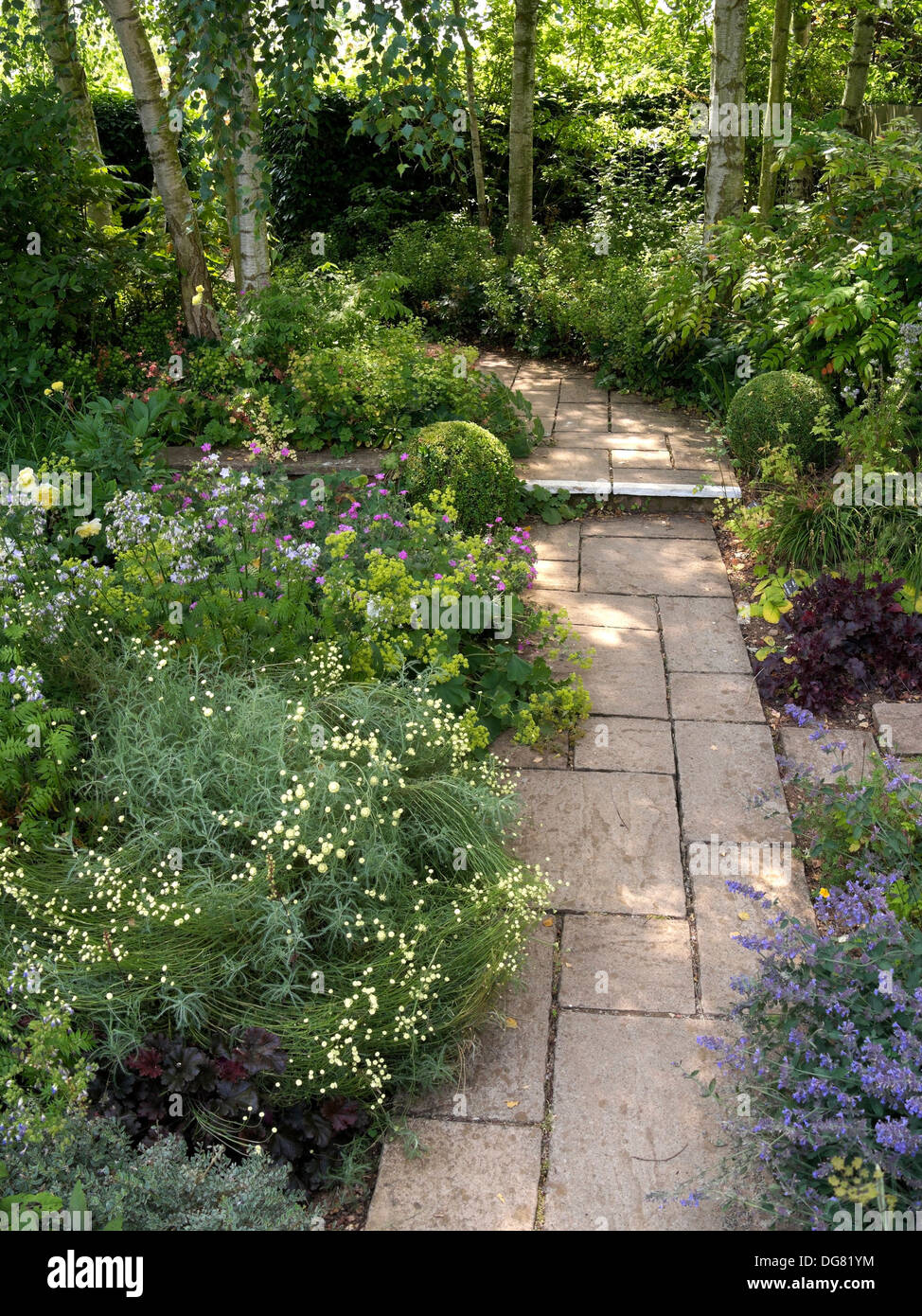 Atractivo jardín pavimentado camino curvo entre fronteras, Barnsdale Jardines, Oakham, Rutland, Inglaterra, Reino Unido. Foto de stock